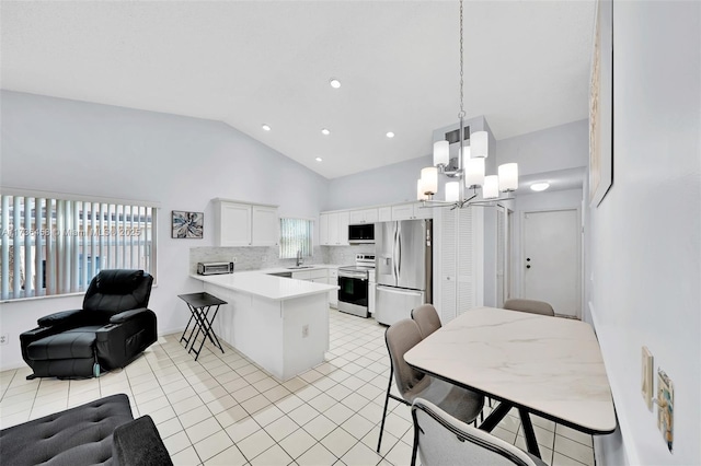 kitchen with decorative light fixtures, white cabinetry, light tile patterned floors, kitchen peninsula, and stainless steel appliances