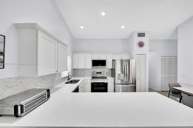 kitchen with sink, white cabinets, backsplash, kitchen peninsula, and stainless steel appliances