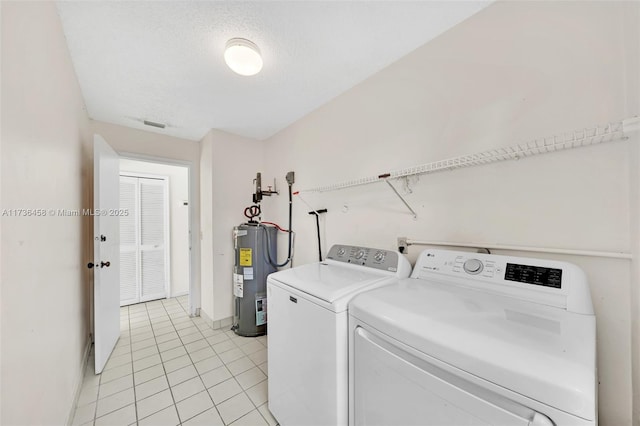 laundry room featuring light tile patterned floors, a textured ceiling, electric water heater, and washing machine and clothes dryer