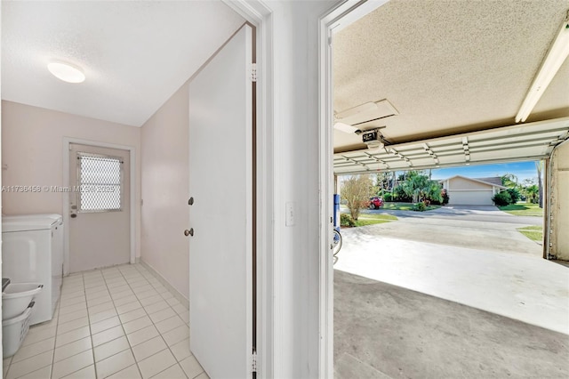 hall with separate washer and dryer, a textured ceiling, and light tile patterned floors