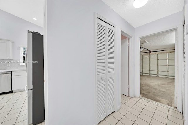 corridor with a textured ceiling and light tile patterned floors