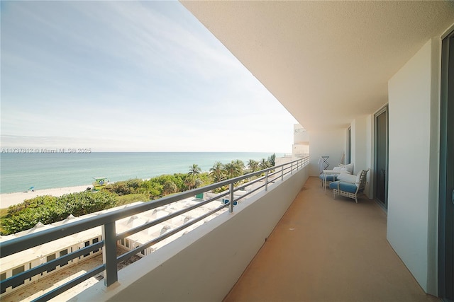 balcony with a water view and a view of the beach