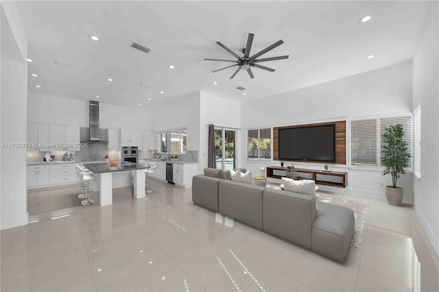 living area featuring recessed lighting, a ceiling fan, light tile patterned flooring, and a towering ceiling