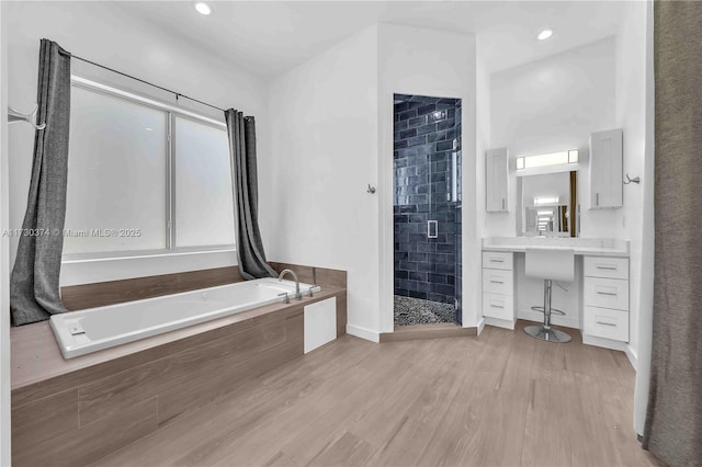 bathroom featuring a shower stall, a garden tub, wood finished floors, and recessed lighting