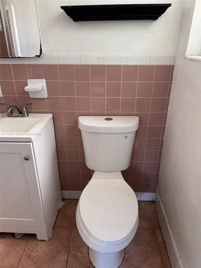 bathroom featuring tile patterned flooring, vanity, tile walls, and toilet