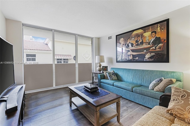 living room with a textured ceiling, visible vents, a wall of windows, and wood finished floors