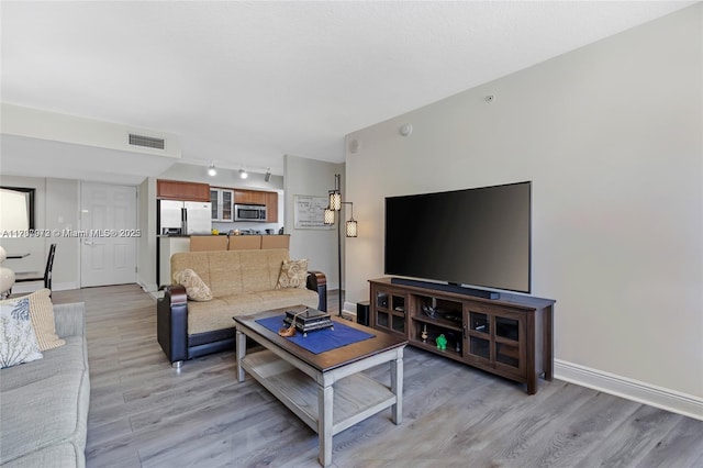 living area featuring light wood finished floors, rail lighting, visible vents, and baseboards