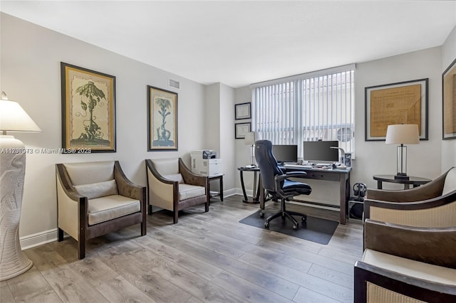 home office with light wood-style flooring, visible vents, and baseboards