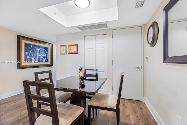 dining area featuring wood finished floors, visible vents, and baseboards