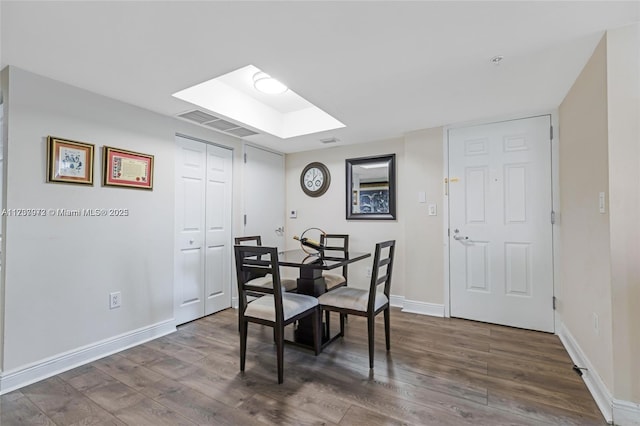 dining space with a skylight, baseboards, visible vents, and dark wood finished floors