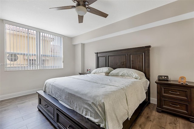 bedroom with dark wood-style floors, a ceiling fan, and baseboards