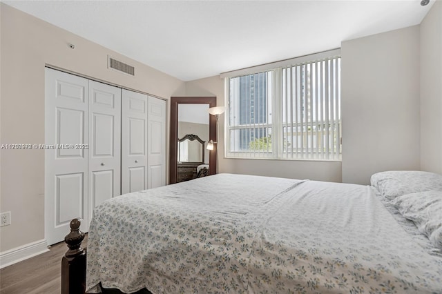 bedroom featuring dark wood-style flooring, a closet, visible vents, and baseboards