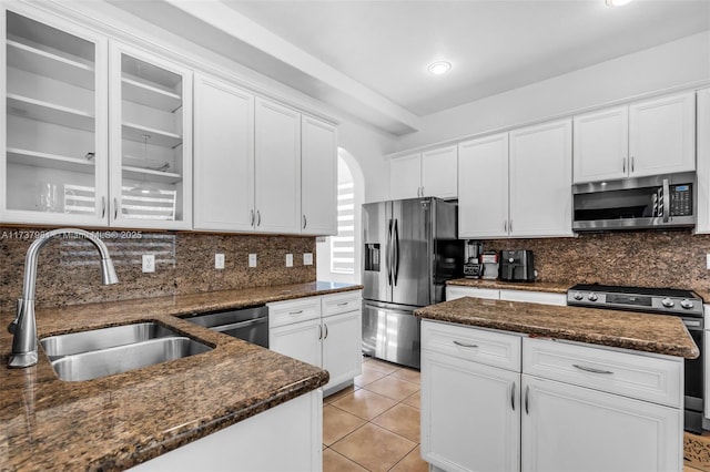 kitchen with sink, stainless steel appliances, dark stone counters, and white cabinets