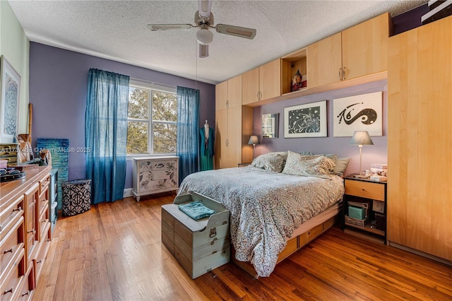 bedroom featuring ceiling fan, hardwood / wood-style floors, and a textured ceiling