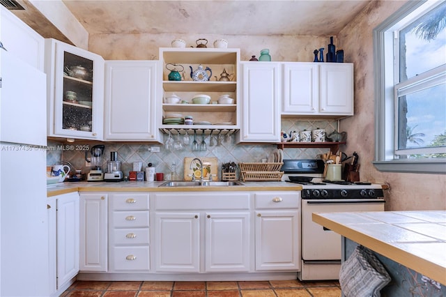 kitchen with white cabinetry, sink, tile counters, and white gas range oven