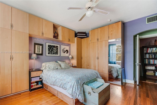 bedroom with ceiling fan, a textured ceiling, and light hardwood / wood-style flooring