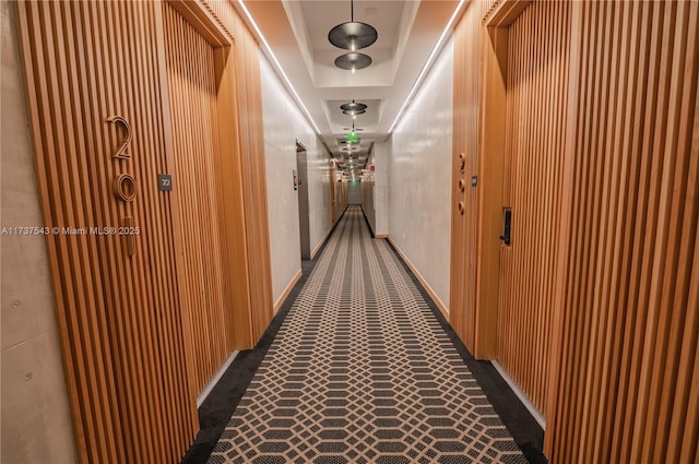 corridor featuring dark carpet and a tray ceiling