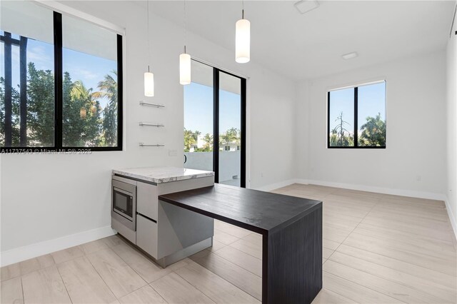 kitchen with hanging light fixtures, a kitchen island, stainless steel microwave, and dark stone counters