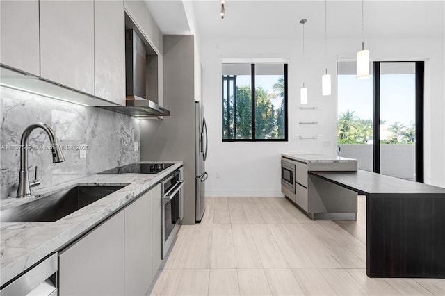 kitchen with sink, decorative light fixtures, appliances with stainless steel finishes, a kitchen island, and light stone countertops