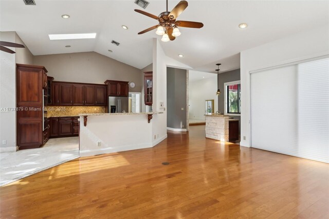 kitchen featuring stainless steel appliances, a kitchen breakfast bar, a skylight, and light hardwood / wood-style flooring