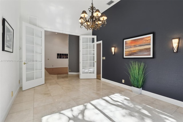 empty room featuring a high ceiling, a notable chandelier, and french doors