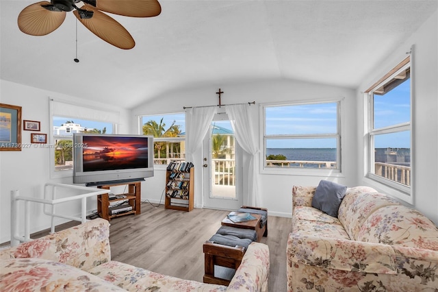 living room with ceiling fan, vaulted ceiling, and light wood-type flooring