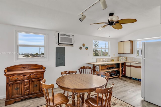 dining room featuring vaulted ceiling, electric panel, ceiling fan, a wall unit AC, and light hardwood / wood-style flooring