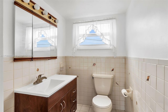 bathroom featuring vanity, tile walls, and toilet