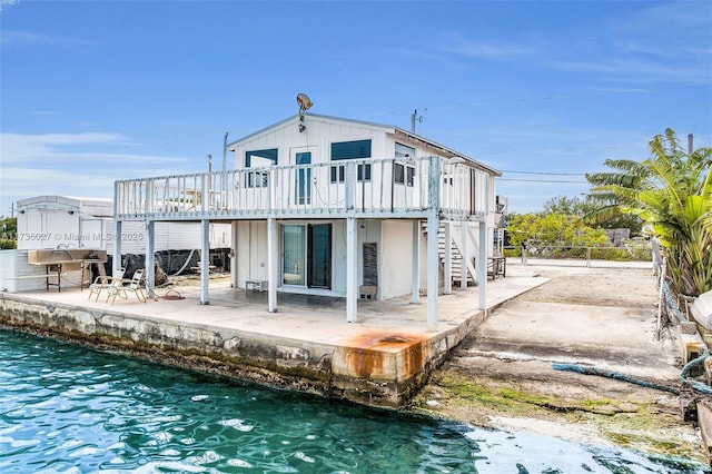 rear view of house with a deck with water view and a patio