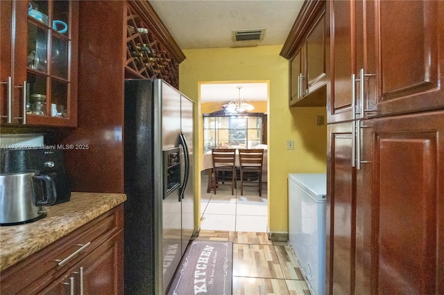 kitchen featuring washer / dryer, a chandelier, stainless steel fridge with ice dispenser, light stone countertops, and light wood-type flooring