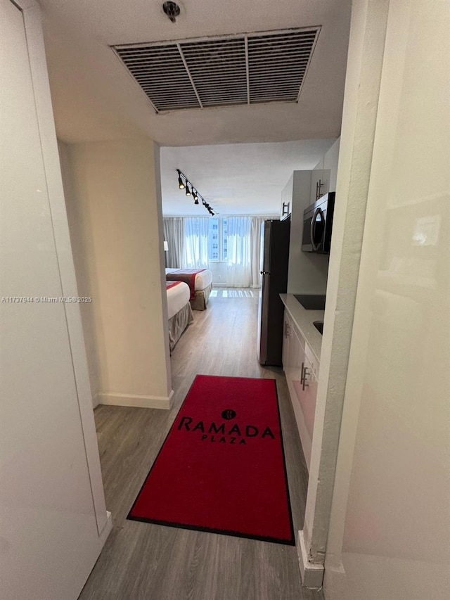 corridor featuring rail lighting and hardwood / wood-style floors