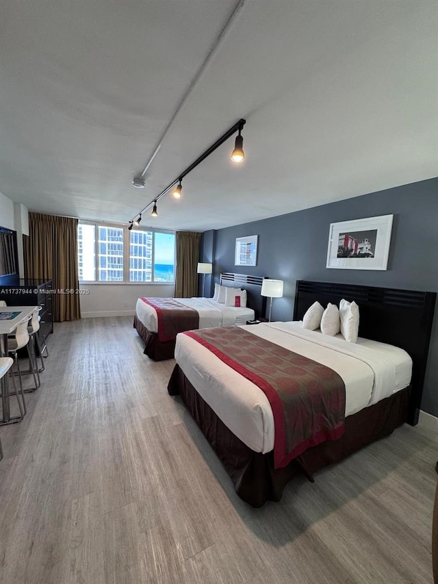 bedroom with rail lighting and light wood-type flooring