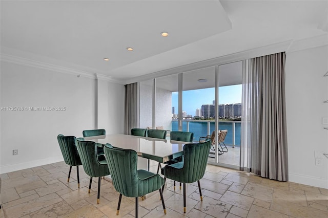 dining space with ornamental molding and a water view