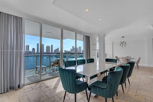 dining area with ornate columns, a water view, a notable chandelier, and expansive windows