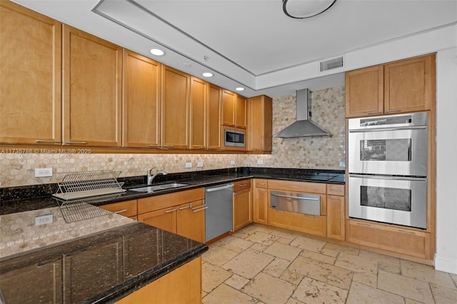 kitchen featuring tasteful backsplash, sink, dark stone counters, stainless steel appliances, and wall chimney exhaust hood