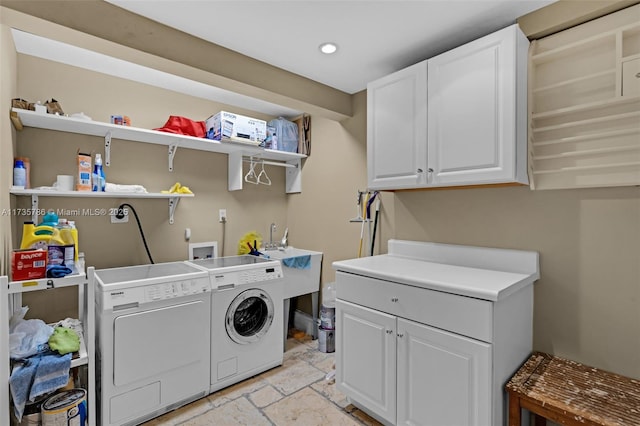 laundry area featuring cabinets, separate washer and dryer, and sink