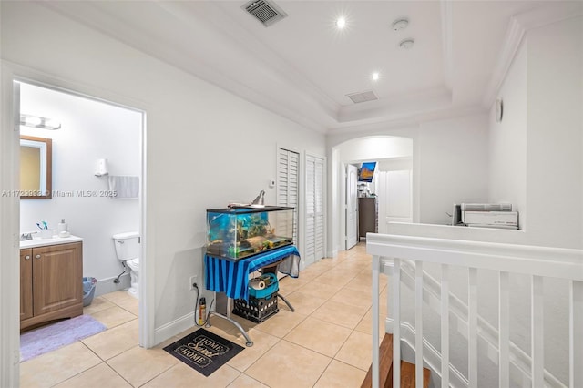 interior space featuring crown molding, connected bathroom, a raised ceiling, and a closet