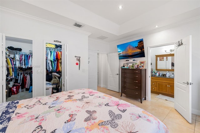 bedroom featuring ensuite bathroom, ornamental molding, a raised ceiling, and light tile patterned flooring