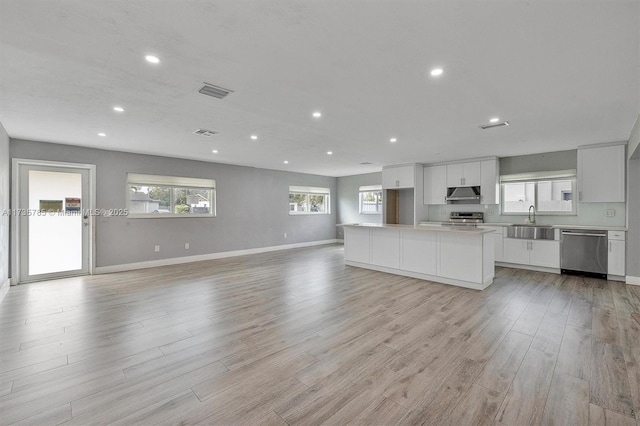 kitchen with sink, white cabinetry, stainless steel appliances, a kitchen island, and light wood-type flooring