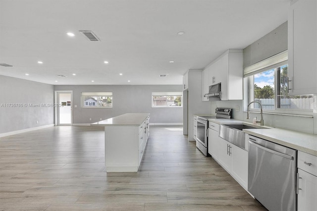 kitchen with appliances with stainless steel finishes, a center island, sink, and white cabinets