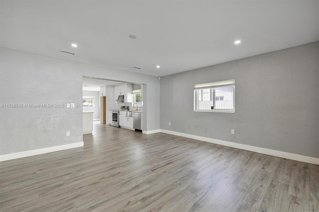 unfurnished living room featuring sink and light hardwood / wood-style flooring