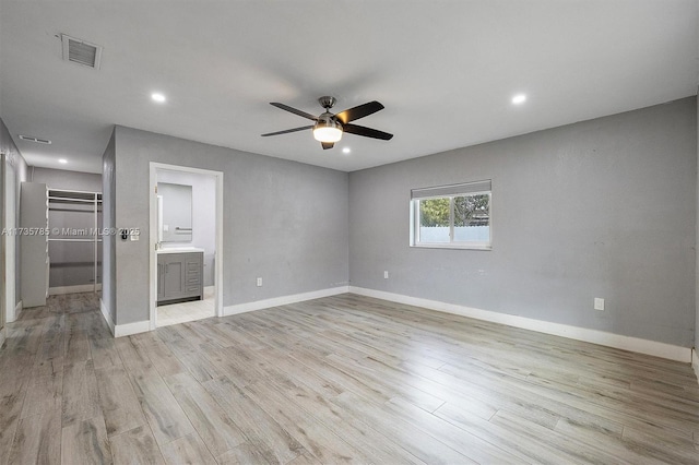 interior space with light hardwood / wood-style flooring, ceiling fan, ensuite bathroom, a spacious closet, and a closet