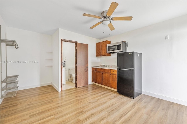 kitchen featuring black refrigerator, ceiling fan, sink, and light hardwood / wood-style flooring