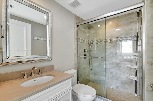 bathroom featuring vanity, toilet, and a shower with shower door