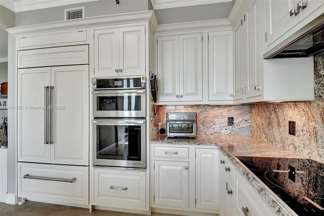 kitchen featuring black electric cooktop, paneled built in refrigerator, double oven, and white cabinets