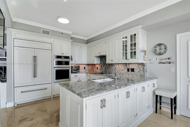 kitchen featuring light stone countertops, stainless steel double oven, white cabinets, and kitchen peninsula