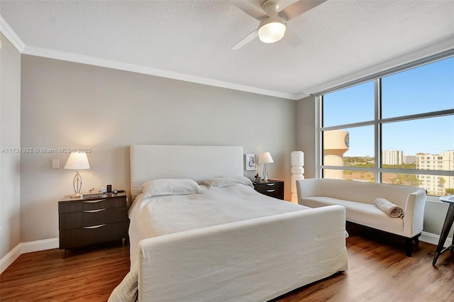 bedroom featuring ceiling fan, dark wood-type flooring, ornamental molding, and a textured ceiling