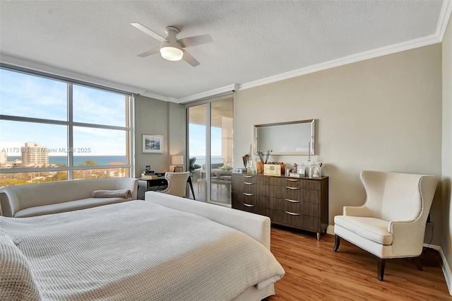 bedroom featuring ceiling fan, crown molding, light hardwood / wood-style floors, and a textured ceiling