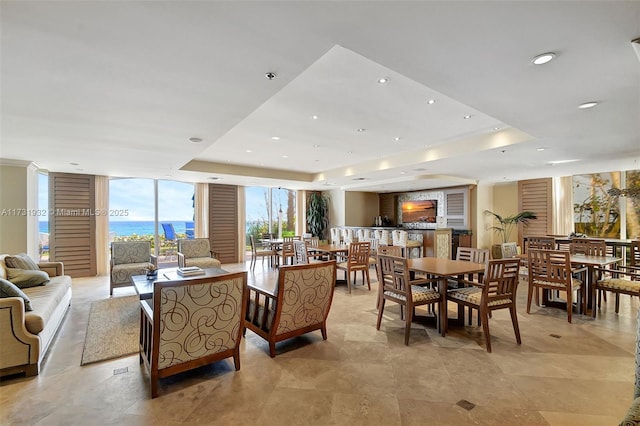 dining space featuring a raised ceiling, a water view, and expansive windows