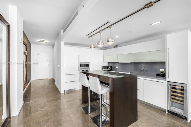 kitchen featuring white cabinetry, stainless steel microwave, beverage cooler, and a kitchen island